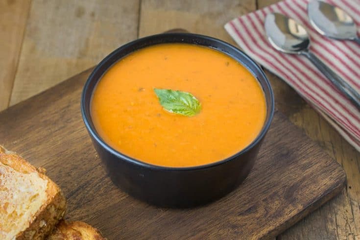 A bowl of 30 minute tomato basil soup on a board