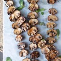 4 skewers of mushrooms on a marble board