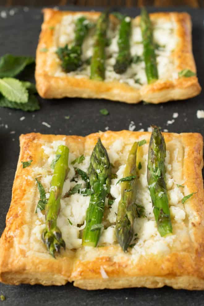 A closeup showing asparagus sprigs on top of a puff pastry tartlet