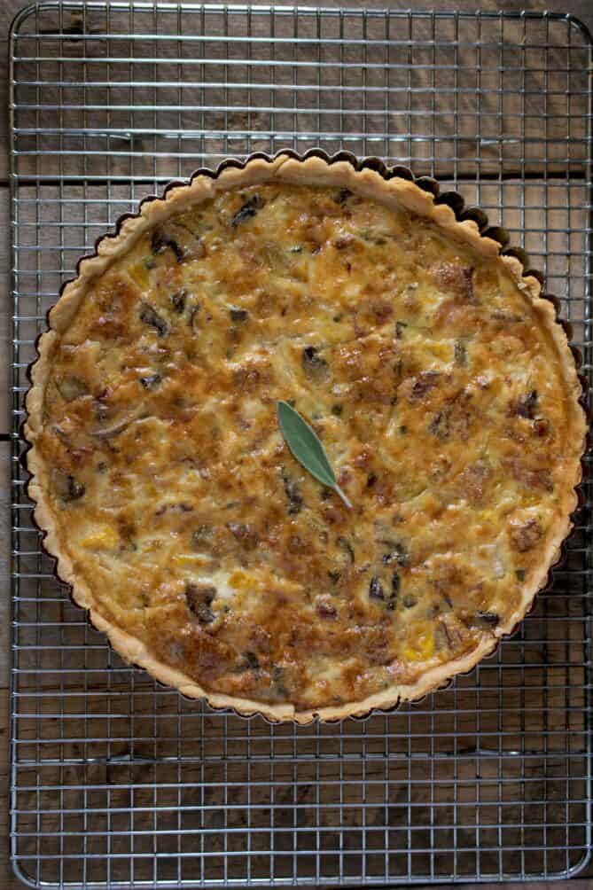 An overhead view of a quiche cooling on a wire rack