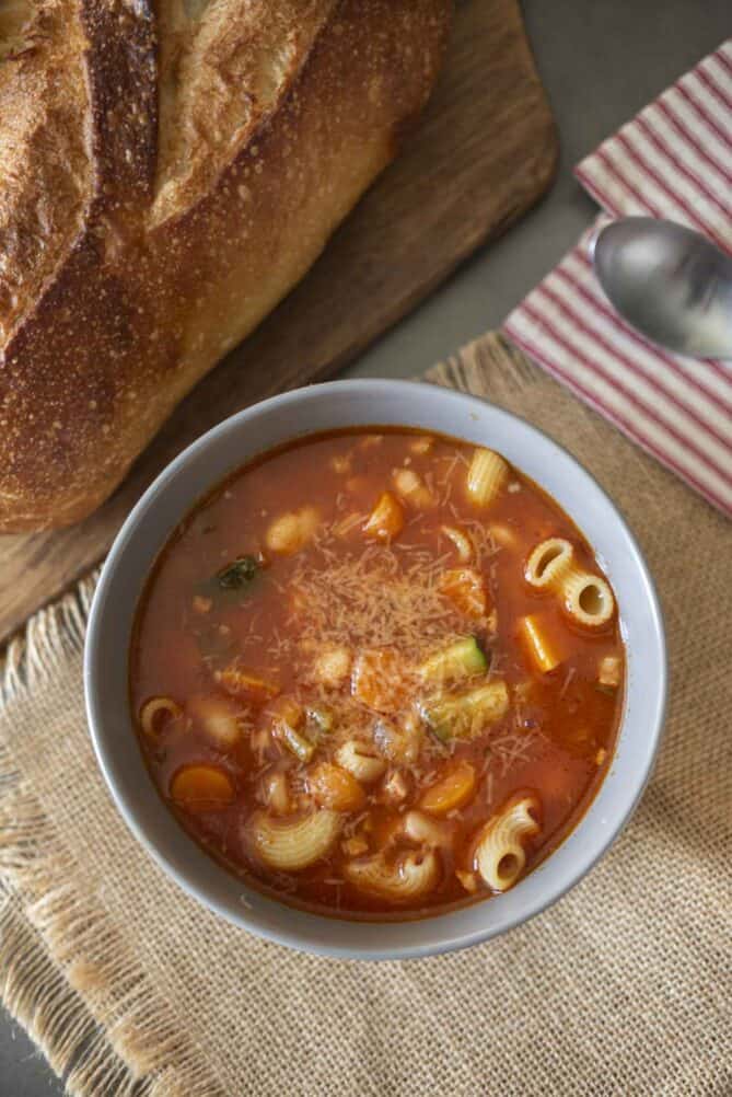 Hearty pasta in vegetable minestrone soup with a crusty loaf of bread