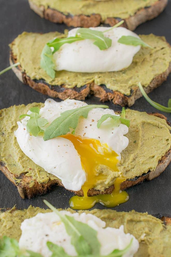 A perfectly poached egg with the yolk running out onto avocado artichoke toast
