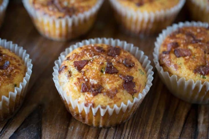 A bacon cheddar corn muffins with pieces of bacon on the top