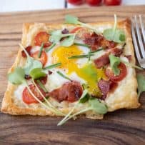 Bright yellow egg yolk running over the puff pastry and crispy bacon