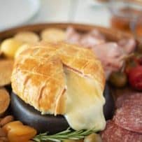 A cut open Baked Brie and Black Forest ham in puff pastry with lots of melted brie oozing out