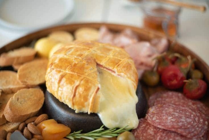 A cut open Baked Brie and Black Forest ham in puff pastry with lots of melted brie oozing out