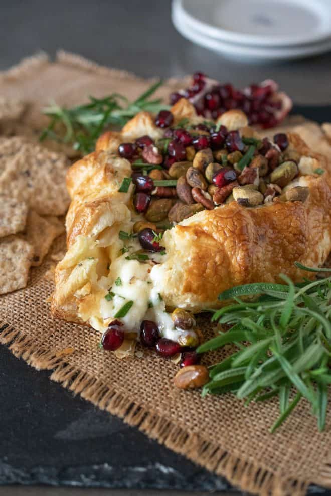 Creamy brie oozing out from the puff pastry with pomegranate seeds and pistachio nuts