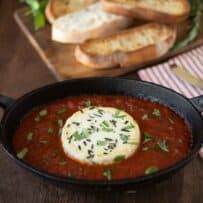 Baked herb goat cheese with marinara sauce in a black oval bowl