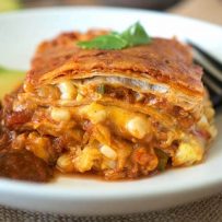 A slice on a white plate showing the layers with salsa and sliced avocado