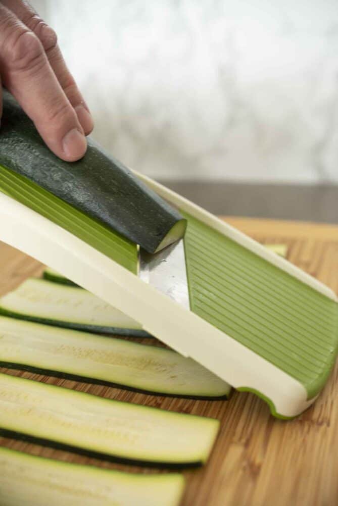 Slicing zucchini on a mandoline slicer
