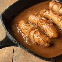 Sausage bangers in a pan with onion gravy