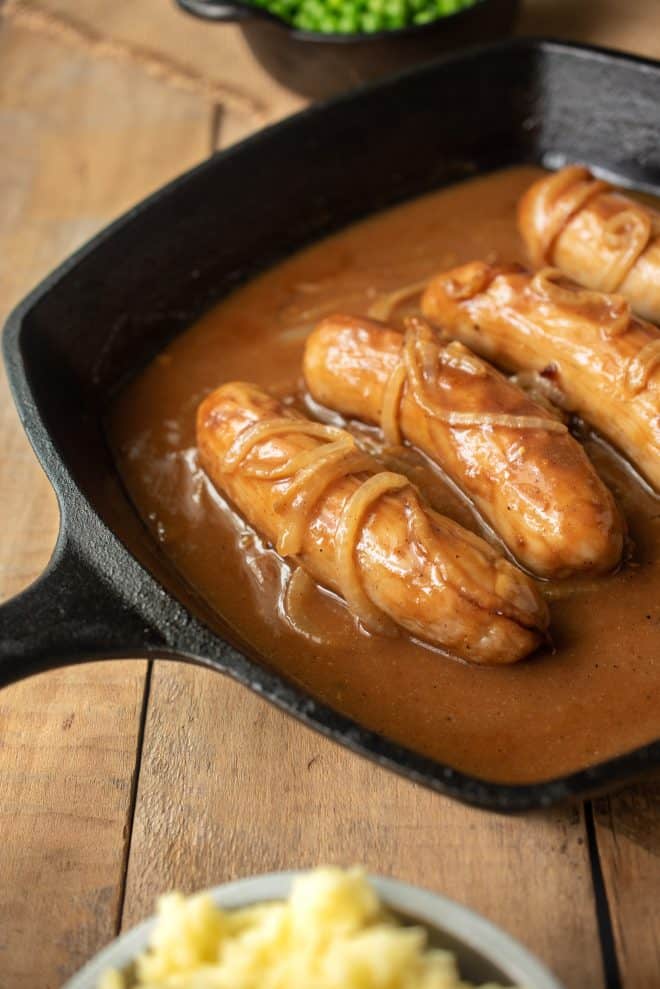 Sausage bangers in a pan with onion gravy