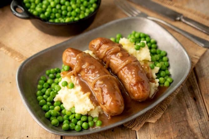 2 British bangers served with fresh peas, mash and onion gravy
