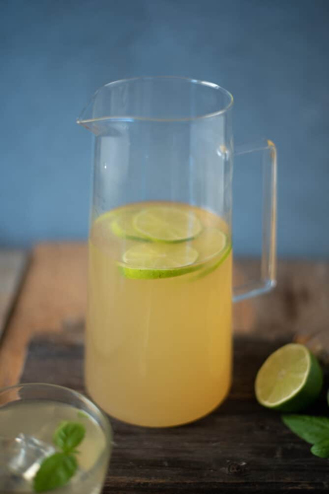 A glass pitcher filled with a herbal tea with lime slices