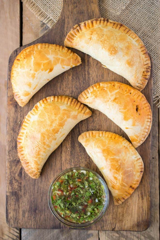 Empanadas viewed from overhead on a board with sauce