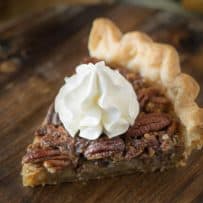 A slice of Bourbon Pecan Pie topped with whipped cream