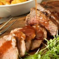 Sliced Tri tip getting drizzled with barbecue sauce