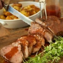Carving slices of the Tri tip on a board with micro greens