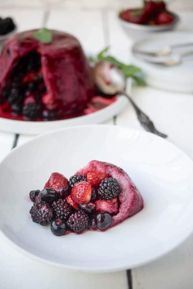 Fresh blackberries, blueberries, strawberries and raspberries in a white bowl with juice soaked bread