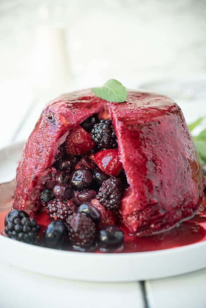 Strawberries, raspberries, blueberries and blackberries spilling out of a bread made pudding