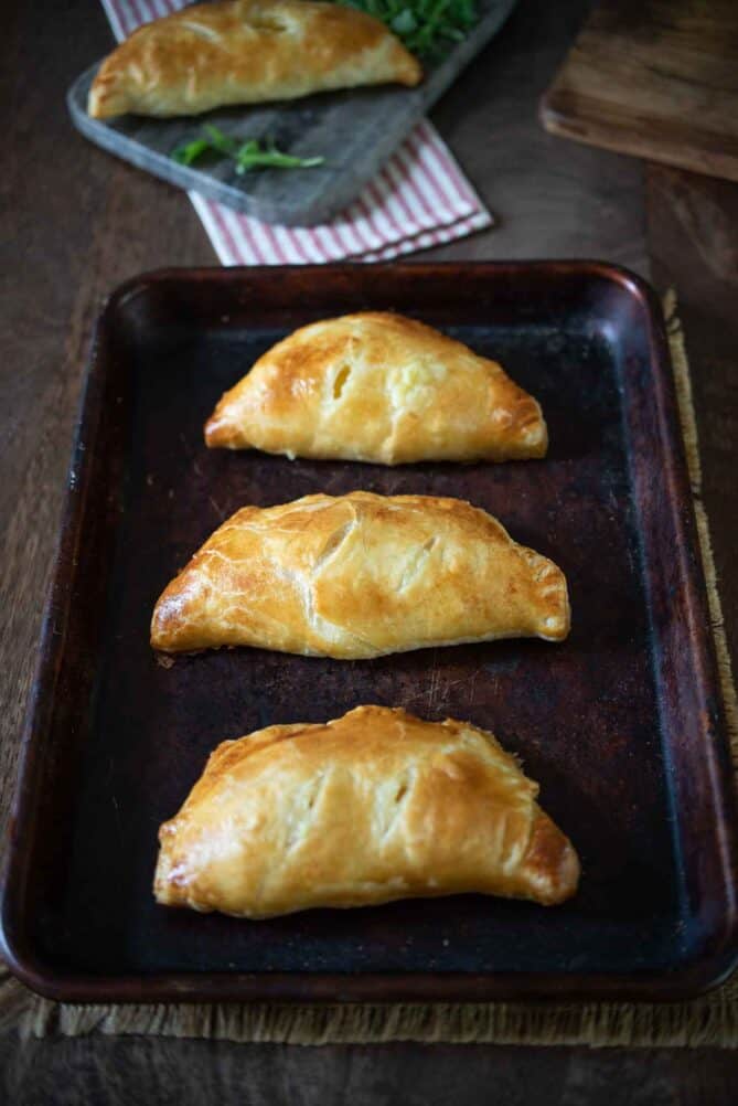 3 cheese and onion pasties on a baking sheet