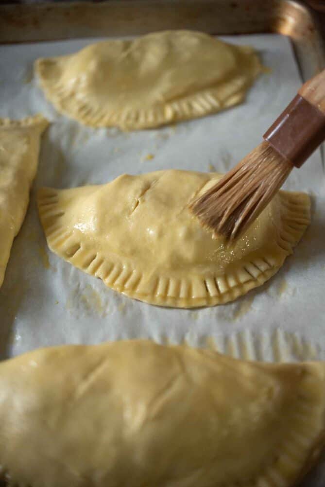 Brushing egg wash on pasties before baking