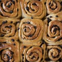 9 browned Chelsea buns dotted with dried currants in right out of the oven