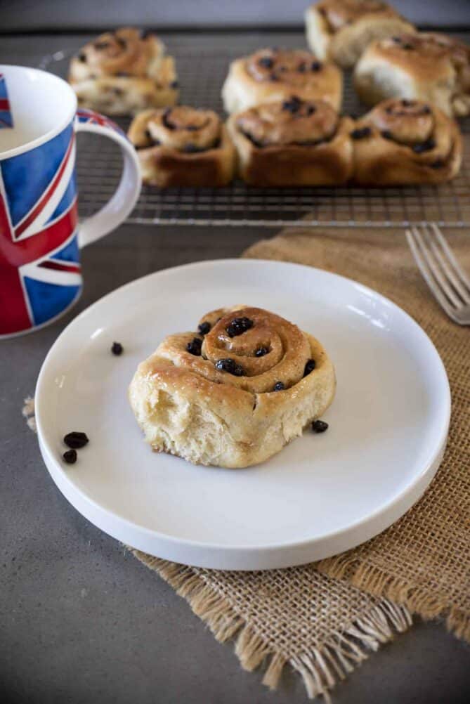 A single Chelsea bun/roll on a round white plate