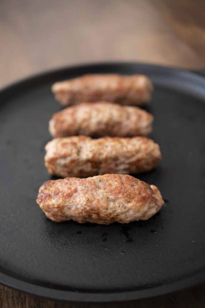 4 British pork sausages lined up in a cast iron pan
