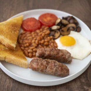 A full English breakfast with sausage, beans, fried egg, mushrooms, tomato and toast