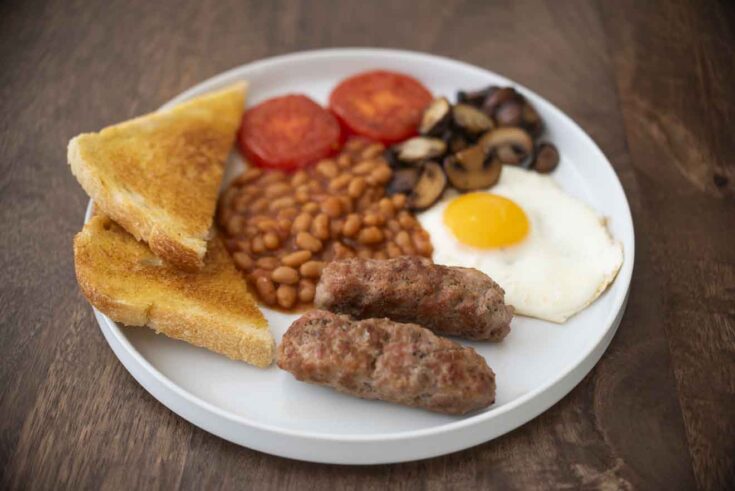 A full English breakfast with sausage, beans, fried egg, mushrooms, tomato and toast