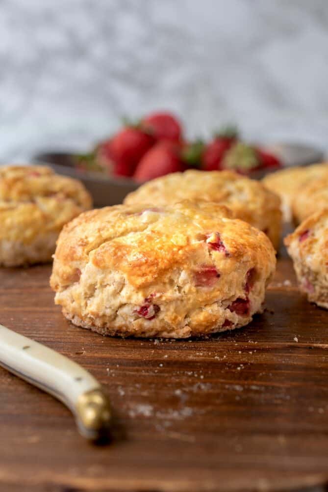 The side of a British scone dotted with fresh strawberries.