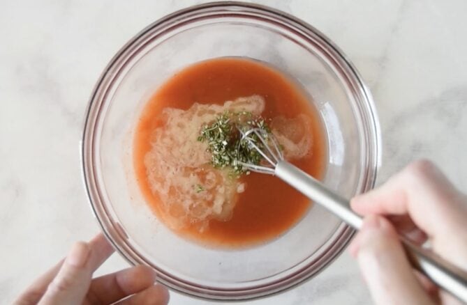 Whisking buffalo sauce, melted butter and fresh rosemary