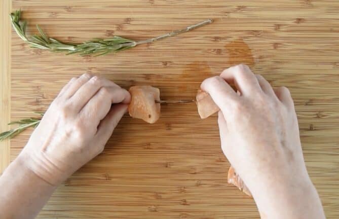 Threading chicken onto rosemary skewers