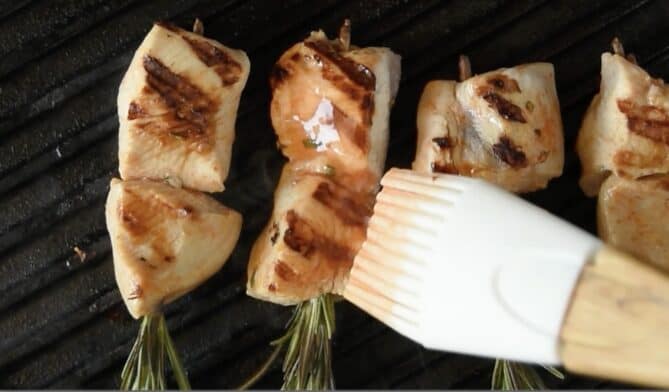 Brushing grilling chicken with marinade