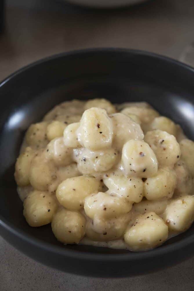 A closeup of a creamy pecorino sauce over gnocchi