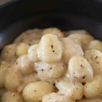 Cheesy creamy pecorino cheese sauce with flecks of black pepper coating gnocchi