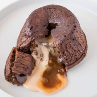 Chocolate lava cake cut open with center oozing out.
