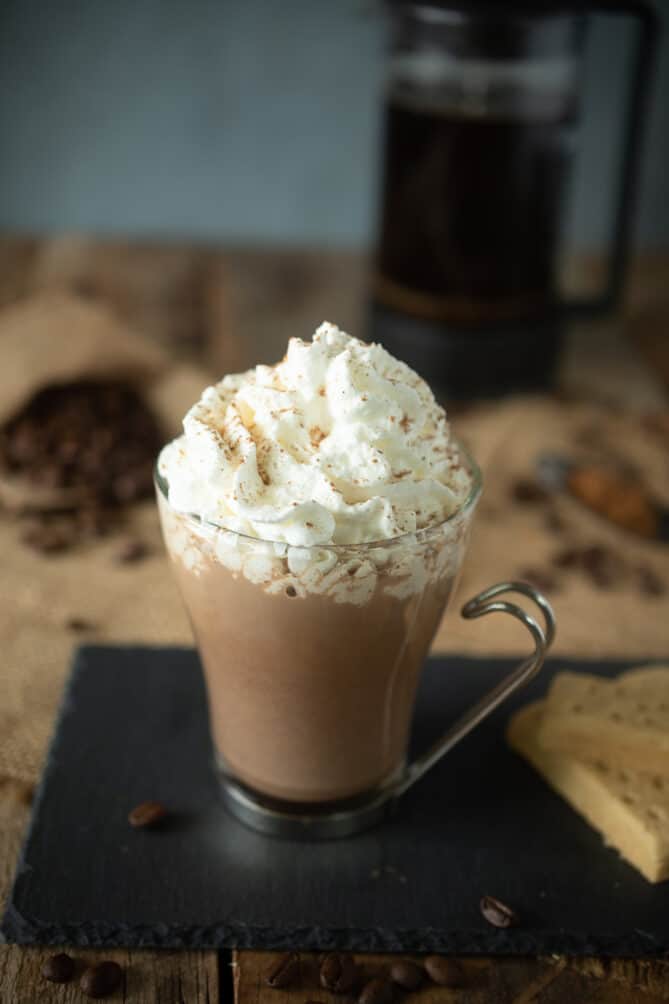 A glass mug of mochachino served with cookies
