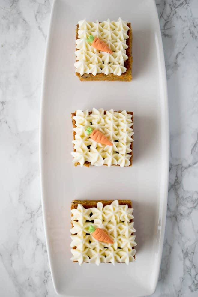 3 carrot cake slices on a white oblong plate
