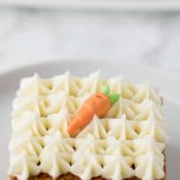 A closeup of a slice of carrot cake topped with cream cheese frosting