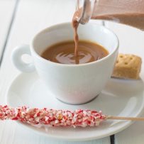 Pouring the creamer into a white cup on a saucer