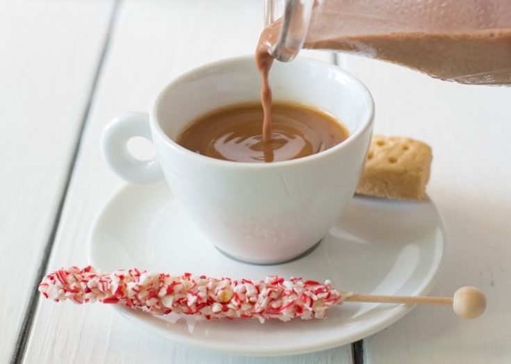 Pouring the creamer into a white cup on a saucer