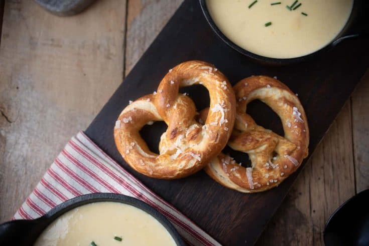 2 cheese stuffed pretzels on a board served with soup