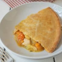 A slice of chicken pot pie with winter vegetables on a white plate