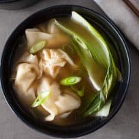 Green bok choy, sliced spring onions and chicken wontons on broth