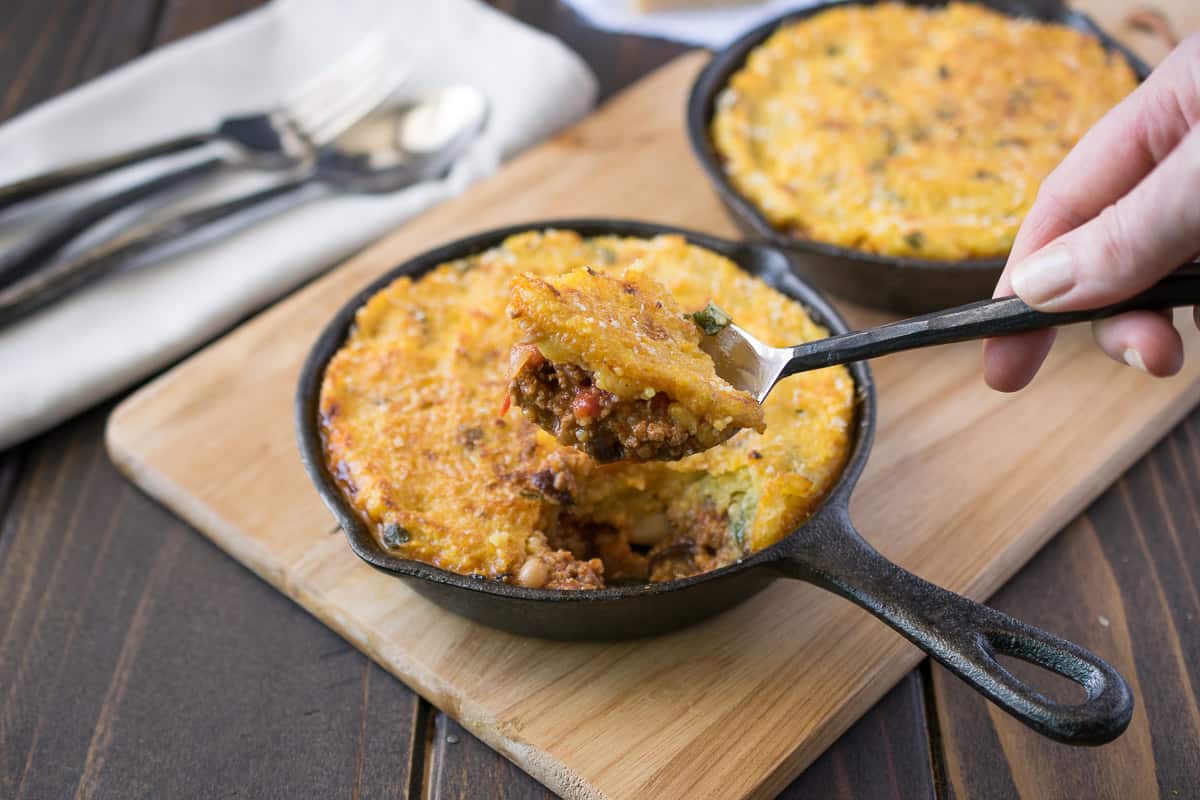Scooping chili polenta pie out of a skillet