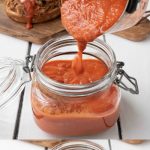 Chipotle bacon bbq sauce being poured from a pan into a glass storage jar