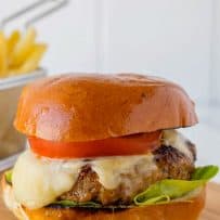 A juicy burger on a bun with melted cheese, lettuce and tomato