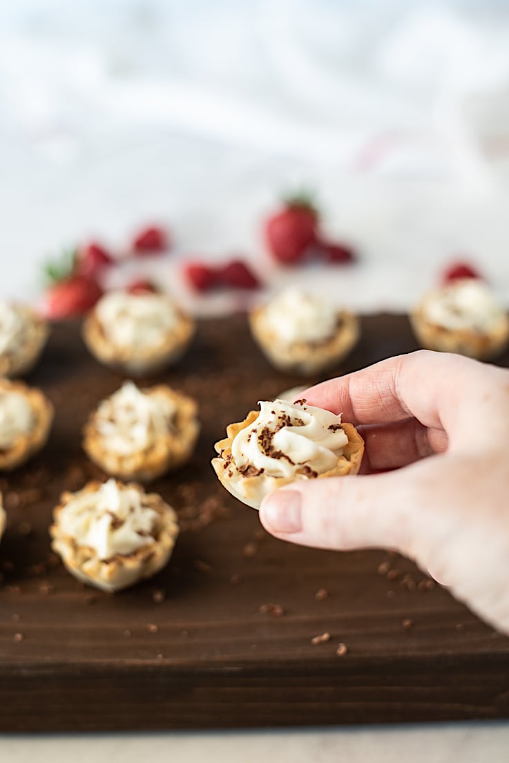 A hand holding a Chocolate mousse and vanilla phyllo dessert cup ready to eat